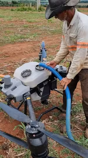 Produtor abastecendo o tanque do drone pulverizador DJI Agras no campo