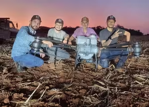 Equipe da Próspera ao lado do drone DJI Agras na lavoura ao entardecer